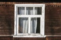 old wooden window with painted white peeling paint on wooden plank wall of village house Royalty Free Stock Photo