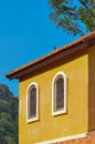 Old wooden window shutter and roof tiles on yellow color wall with blue sky beautiful exterior vintage architecture building. Royalty Free Stock Photo