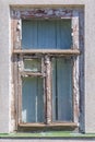 Old wooden window with a vent pane and the remains of white paint on the wall Royalty Free Stock Photo