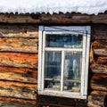 Old wooden window in winter, roof of the brown house covered with snow