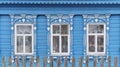 Old wooden windows with carved architraves. Blue facade of typical rural Russian house. Royalty Free Stock Photo