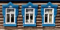 Old wooden windows with carved architraves. Log facade of typical rural Russian house. Royalty Free Stock Photo