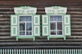 Old wooden windows with carved architraves. Log facade of typical rural Russian house. Royalty Free Stock Photo