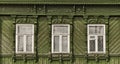 Old wooden windows with carved green architraves on green facade of Russian house. Royalty Free Stock Photo