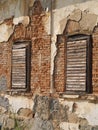 Old wooden windows on a damaged house facade Royalty Free Stock Photo