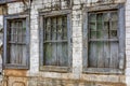 Old wooden windows ruined by time on the facade of abandoned house