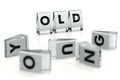 OLD word written on glossy blocks and fallen over blurry blocks with YOUNG letters, isolated on white background. Old means more