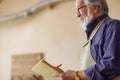 Old worker with moustache nad beard holding notepad