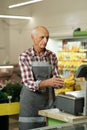 Old worker weighing bananas on scales in a store or supermarket. Retail concept Royalty Free Stock Photo