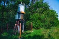 Old working rural electrical distribution transformer in the forest. Sunny day, the concept of industrial. Royalty Free Stock Photo