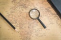 An old world map, a magnifying glass, a pencil and a notepad Royalty Free Stock Photo