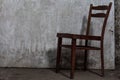 Old worn chair with cracks is on a concrete floor in an abandoned