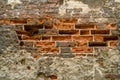 Old red brick wall with crumbled bricks, cracked concrete, erosion big black stone granite foundation texture background Royalty Free Stock Photo