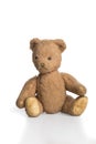 Old worn down teddy bear sitting isolated in white