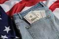 Old worn jeans are lying on flag United States America and there are hundred dollar bills in pocket Royalty Free Stock Photo