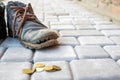 Old worn leather boot in dark blue with colorful brown laces. Poverty concept. Old and torn shoes and thrown to the ground coins. Royalty Free Stock Photo