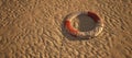 Old worn lifebuoy lying in rippled sand of beach. Royalty Free Stock Photo