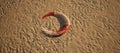 Old worn lifebuoy lying in rippled sand of beach. Royalty Free Stock Photo