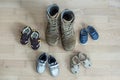 Old worn military boots and lot of baby shoes on wooden floor. Military father and family concept Royalty Free Stock Photo