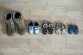 Old worn military boots and lot of baby shoes on wooden floor. Military father and family concept Royalty Free Stock Photo