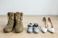 Old worn military boots, women\'s shoes and baby shoes on wooden floor. Veteran and family concept