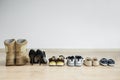 Old worn military boots, women`s shoes and lot of baby shoes on wooden floor. Back