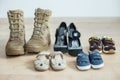 Old worn military boots, women`s shoes and lot of baby shoes on wooden floor Royalty Free Stock Photo