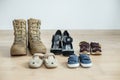 Old worn military boots, women`s shoes and lot of baby shoes on wooden floor Royalty Free Stock Photo