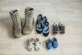 Old worn military boots, women`s shoes and lot of baby shoes on wooden floor. Top view Royalty Free Stock Photo