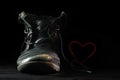 Old worn out black shoe in love forms a blushing red heart with