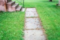 Old worn out cement side walk surrounded by grass