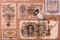 Old worn out of circulation ruble banknotes of tsarist russia and a watch on a chain on a brown background. Close-up top view