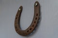 An old worn-out and rusty metal horseshoe nailed to the light grey wooden door of a village house. Horseshoe is a sign of fortune Royalty Free Stock Photo