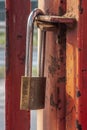 Old worn padlock locked on the paint-shabby gate. Metaphor of a liquidated business.