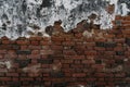 Old and worn red brick wall face with white and black cement coating peeling away