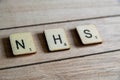 Old worn vintage wooden textured cubes with letters spelling NHS. British National Health Service