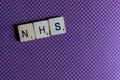 Old worn vintage wooden textured cubes spelling out NHS, the British National health Service,