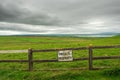 Old worn warning sign `Private property` on a fence by a green field, Grey cloudy sky, Royalty Free Stock Photo