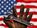 Old worn work glove holding adjustable wrench with Forged Steel text. Strong American workforce or industry, or America labor Royalty Free Stock Photo