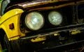 Old wrecked car in vintage style. Abandoned rusty yellow car in the forest. Closeup front view headlights of rusty wrecked abandon Royalty Free Stock Photo