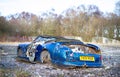 An old wrecked sports car sits on the ground