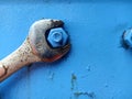 Old wrench is tightening the nut on the blue metal plate. Corroded and rusty Spanner Royalty Free Stock Photo