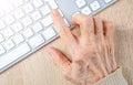 Old wrinkled hand of the old woman and computer keyboard