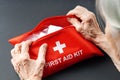 Old wrinkled hands open first aid kit