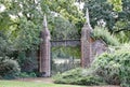 Old wrought iron gates mounted between two tall slim brick gate posts in an English country garden Royalty Free Stock Photo