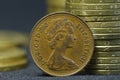 An old, 1980 year, one penny coin with portrait of Queen Elizabeth II put on edge in front of piles of coins Royalty Free Stock Photo