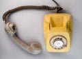 Old yellow antique rotary telephone with grey removed receiver on blue background. Vintage landline home phone with dial Royalty Free Stock Photo