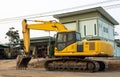 An old yellow backhoe parked on the roadway being renovated near high-voltage power lines