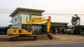 An old yellow backhoe parked on the roadway being renovated near high-voltage power lines