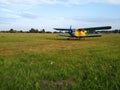 An old yellow biplane with blue wings and a running engine drives through a field of green grass Royalty Free Stock Photo